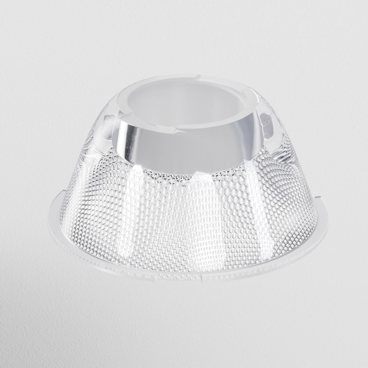 A clear, textured, funnel-shaped plastic object with a metallic interior on a white background features a hexagonal pattern. It resembles the Focus LED Track Light Lens ⌀55mm 36°, designed for customizable lighting and offering a 36° beam angle.