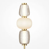 The Pattern LED Table Lamp - Gold features an energy-efficient design with a gold base and three vertically stacked glass shades. The top and bottom shades are textured, while the smooth, opaque middle shade provides a warm glow, enhancing the sleek gold metal finish.