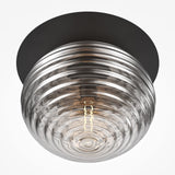 The Reels Ceiling Light features a ribbed smoked glass dome that emits a warm glow. This contemporary black ceiling fixture is mounted on a sleek base.