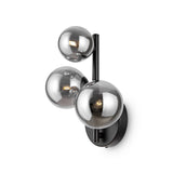 The Dallas 3 Light Wall Light - Black With Smoked Mirrored Glass features three spherical glass globes with a smoky tint, mounted on a sleek black fixture. Each globe encloses a bulb, attached to a circular black base, ideal for modern interiors.