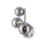 The Dallas 3 Light Wall Light showcases three spherical smoked mirrored glass shades on a chrome-finished frame. It emits a warm glow and mounts on a round base, making it ideal for modern decor.