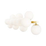 The Dallas 13 Light Wall Light features white glass globes on a sleek, brass frame. The round globes are staggered to cast a soft, diffuse glow.