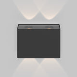 The modern Show Outdoor Wall Light 3000K in graphite is a sleek aluminum, wall-mounted fixture with dual circular LED lights, casting energy-efficient, soft light patterns upward and downward on a white wall—ideal for stylish outdoor lighting.