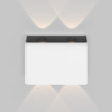 The Show Outdoor Wall Light 3000K - White, mounted on a gray wall, casts soft, warm light upward and downward, creating overlapping patterns. It features a thin black border with an energy-efficient LED and boasts a weather-resistant design for durability in various conditions.