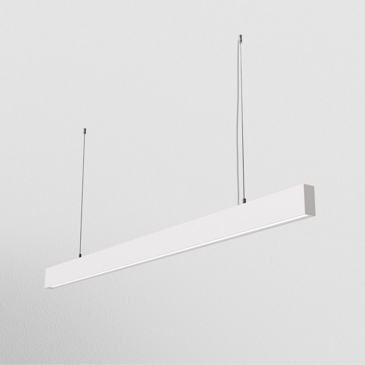 The BASIS LED Linear Suspension Light - White, showcasing a modern aesthetic, hangs from the ceiling by two thin cables against a plain white background.