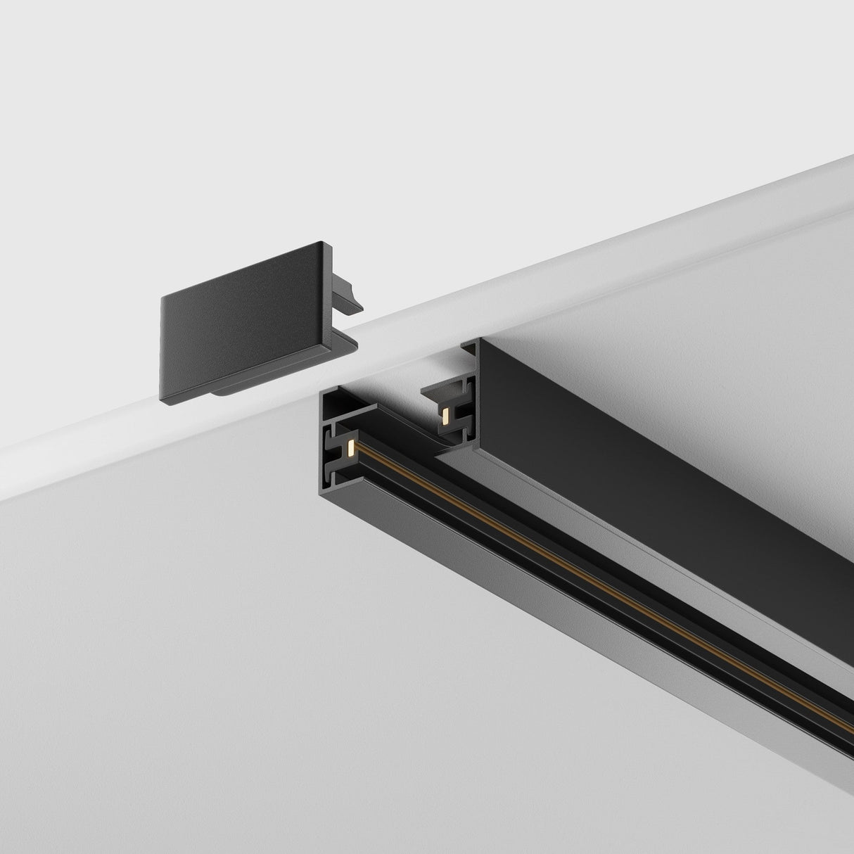 A close-up of the Unity Single Phase Surface-Mounted Track 1m in black, set against a white ceiling for customizable lighting. It shows the sleek black track with an exposed end cap, emphasizing its assembly components and modern finish.