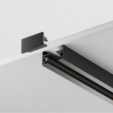 Close-up of a Unity Single Phase Surface-Mounted Track 2m in black, L-shaped and mounted on a white ceiling. A detached end cap near the rail’s open end shows inner components and wiring channels, ideal for customized lighting setups.
