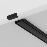 A close-up of the Radity Magnetic Surface-Mounted Track 2m in black against a white ceiling, ideal for modern interiors. One end is open, showing copper connectors, with a sleek black end cap nearby to complete this elegant lighting solution.