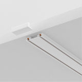 Close-up of a white ceiling with the Radity Magnetic Surface-Mounted Track 2m - White, ideal for modern interiors. This sleek linear fixture features a small rectangular opening for light installation on its magnetic track, with a partially visible white square panel nearby.