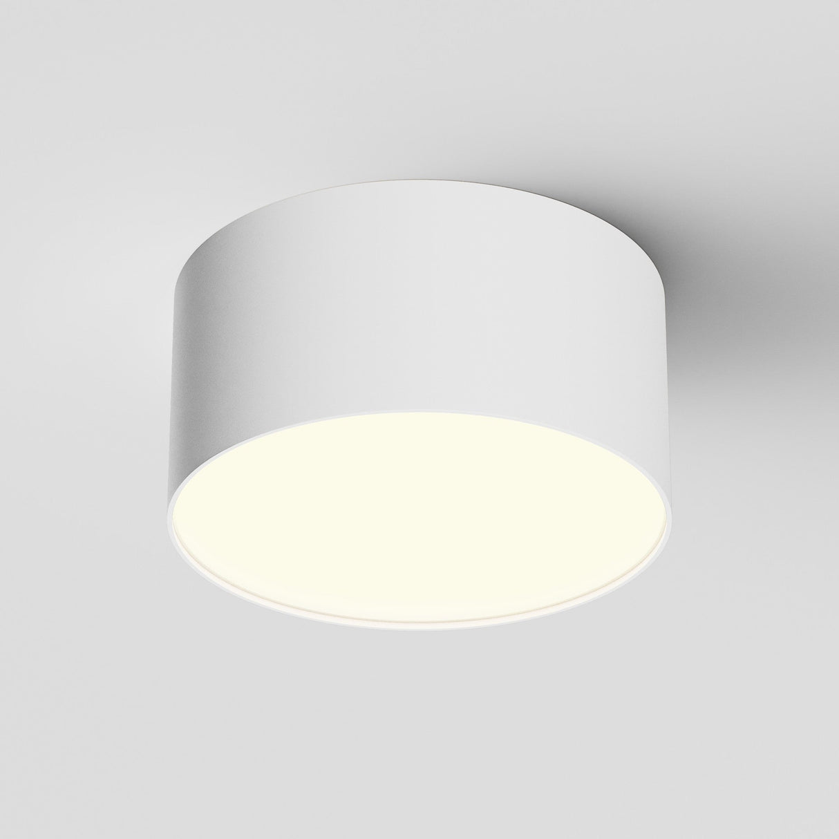 The Zon LED Downlight 3000K 12W - White features a sleek, cylindrical ceiling design with aluminum construction and emits a soft, even glow from its flat underside, beautifully illuminating the surrounding area.