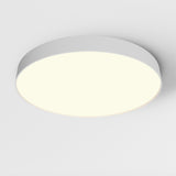 The Zon LED Large Flush Ceiling Light 3000K 90W - White, with its round design, is mounted on a white ceiling, blending seamlessly into the modern interior while emitting a soft, even glow that illuminates the area, embodying minimalist lighting design.