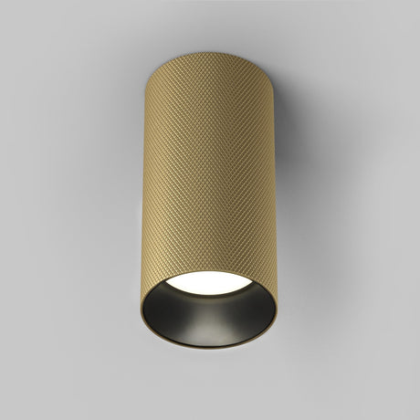 The Artisan Single Fixed Round Surface Mounted Downlight in matte gold is a luxury lighting piece with a textured exterior and smooth black interior, seamlessly mounted on a white ceiling to illuminate downward.