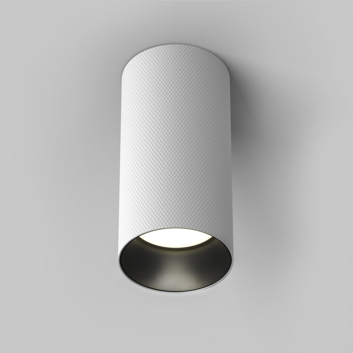 The Artisan Single Fixed Round Surface Mounted Downlight in white boasts a modern cylindrical design and bright bottom emission, seamlessly integrating with plain white ceilings.