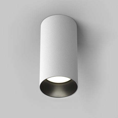 The Artisan Single Fixed Round Surface Mounted Downlight in white boasts a modern cylindrical design and bright bottom emission, seamlessly integrating with plain white ceilings.