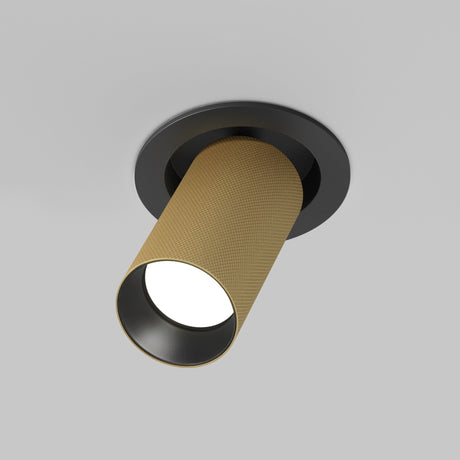 The Artisan Single Tilt Round Recessed Downlight features a cylindrical, matte gold housing with black trim. Seamlessly integrated into the ceiling, it casts a soft glow from its open end against a plain light gray background, exuding modern elegance.
