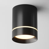 The Orlo LED Round Surface Downlight 9W 3000K - Black features a modern cylindrical design with a matte black finish that emits white light from the bottom and has a thin circumferential gap, adding sleekness to its energy-efficient design against any plain white ceiling.
