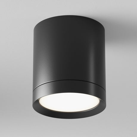 The Hoop Medium Round Surface Downlight - Black is a sleek, cylindrical LED fixture that emits a soft, bright light against a plain white background. Perfect for modern interiors, this stylish downlight enhances any room with its elegant simplicity and energy-efficient design.