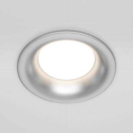 A close-up of the Slim Fixed Round Recessed Downlight - Silver, featuring a circular frame and cast aluminum design, emits a bright glow against the white ceiling.