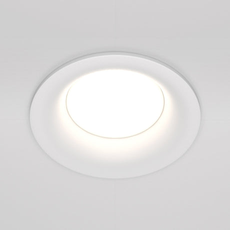 The Slim Fixed Round Recessed Downlight in white is embedded in a plain ceiling, emitting a bright, even glow. Its minimalist design features a smooth trim that blends seamlessly into the ceiling surface.