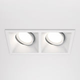 A white ceiling showcases two recessed Dot Twin Tilt Rectangular Downlights, each with circular lights. These fixtures offer a soft glow, highlighting a minimalist, modern aesthetic while being energy-efficient.