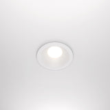 The Zoom Single Fixed Round Recessed Downlight in white is a ceiling-mounted LED with an IP65 rating, emitting bright white light against a smooth white ceiling.