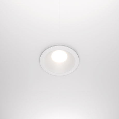 The Zoom Single Fixed Round Recessed Downlight in white is a ceiling-mounted LED with an IP65 rating, emitting bright white light against a smooth white ceiling.