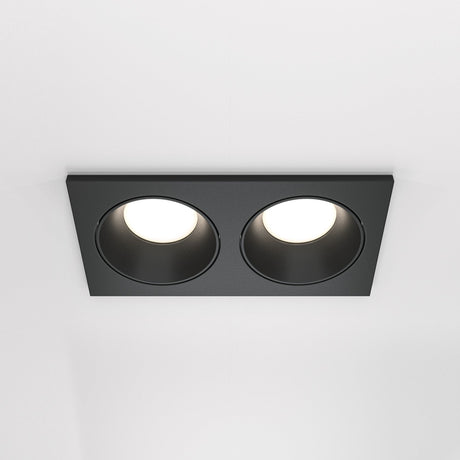 The Zoom Twin Fixed Rectangular Recessed Downlight in black features two circular LED lights elegantly embedded in a white ceiling, offering a modern design with an IP65 rating for enhanced durability.