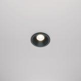 The Zoom LED Round Recessed Downlight 6W 3000K in black casts a soft glow on the plain white ceiling, creating an elegant atmosphere.