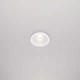 The Zoom LED Round Recessed Downlight 6W 3000K in white is set into the ceiling, casting a soft, focused glow. This circular fixture features a white trim and an IP65 rating for durability, while retaining a minimalist and modern look.