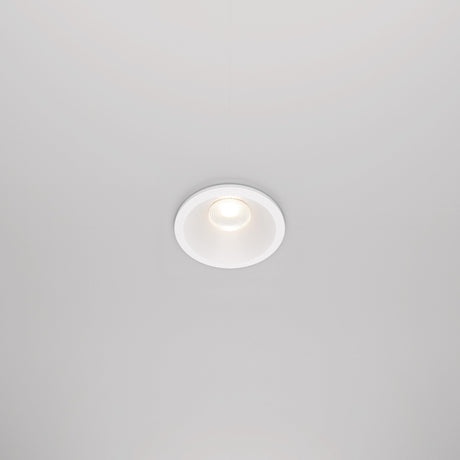 The Zoom LED Round Recessed Downlight 6W 3000K in white is set into the ceiling, casting a soft, focused glow. This circular fixture features a white trim and an IP65 rating for durability, while retaining a minimalist and modern look.