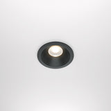 The Zoom LED Dimmable Round Recessed Downlight 12W 3000K - Black softly illuminates with a warm glow and features a black rim against a white background.