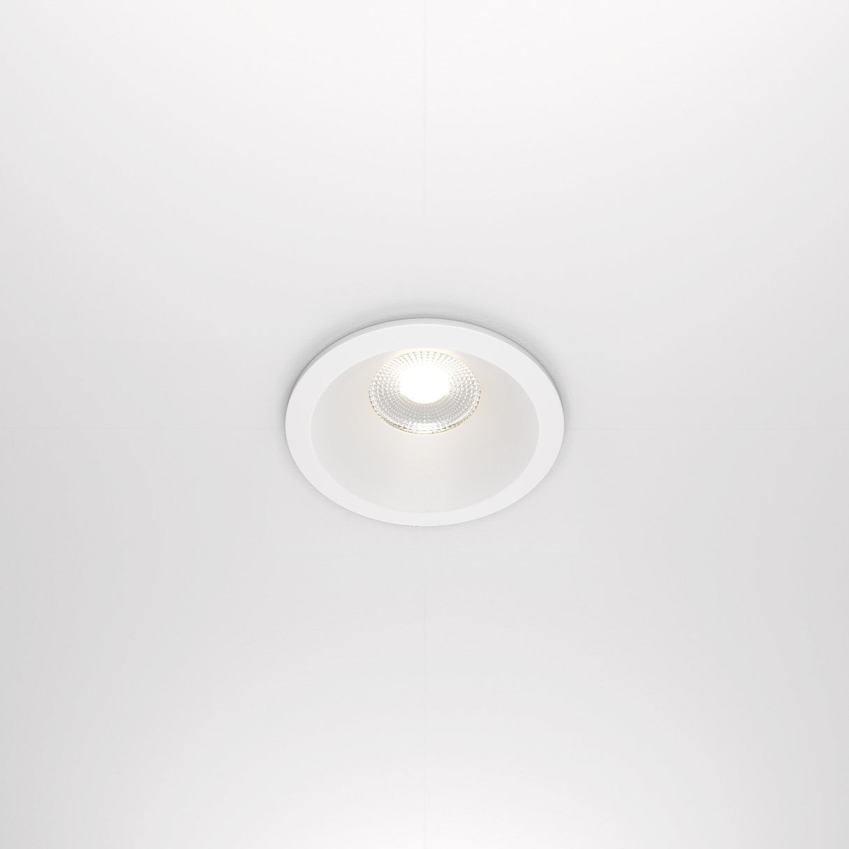 The Zoom LED Dimmable Round Recessed Downlight 12W 4000K - White emits a soft glow from a white ceiling. The light has a grid pattern, delivers excellent illumination with CRI 90 for true color rendering, and is perfectly centered in the image.