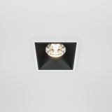 The Alfa LED Dimmable Fixed Square Recessed Downlight 15W 3000K in white and black is turned on, featuring a two-tone design with a centered bulb against a black interior, creating striking contrast and enhancing modern interior lighting.