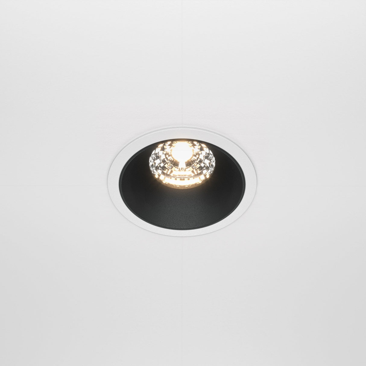 The Alfa LED Fixed Round Recessed Downlight 15W 3000K - White & Black is installed in a white ceiling, offering a modern design with its sleek black inner ring and white outer rim. When on, it casts a bright, warm glow, serving as an ideal contemporary lighting fixture for any space.
