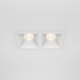A sleek white ceiling features the Alfa LED Dimmable Fixed Square Recessed Twin Downlight, 20W, 3000K. Each fixture has a circular bulb emitting warm white light, showcasing clean lines and symmetry in a modern, minimalist design.