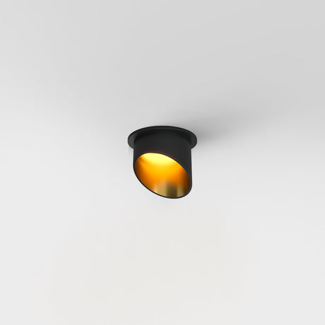 The Lipari Fixed Recessed Downlight - Black & Gold, featuring a sleek cylindrical design and warm golden interior, casts a soft glow. Installed on a white ceiling, it enhances any space with its minimalist and elegant modern lighting.