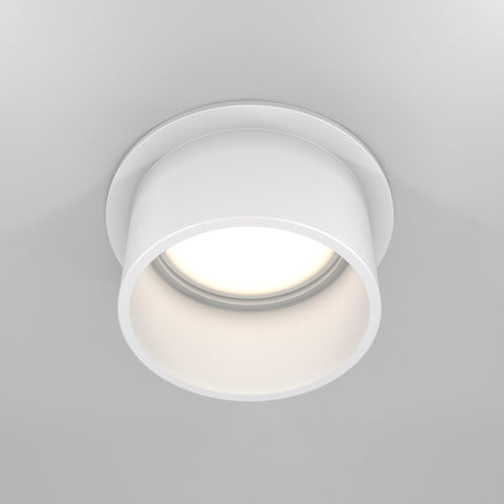 The Reif Round Recessed Downlight with Extended Rim - White is elegantly illuminated and seamlessly fits into a smooth, light-colored ceiling.