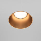 The Share Round Plaster-in Fixed Recessed Downlight in matte gold adds a soft, warm glow against a neutral gray ceiling with its circular design and seamless plaster-in installation.