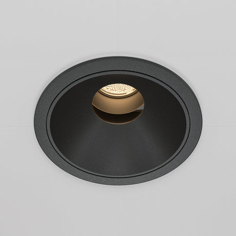 The Wise LED Round Recessed Downlight 10W 3000K - Black showcases a minimalist design with its black circular frame on a white surface, emitting a warm glow that creates an inviting atmosphere, enhanced by its high Colour Rendering Index (CRI).