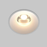The Round LED Recessed Downlight 12W 3000K - White features a faceted reflector, casting a warm glow against a light gray backdrop, ideal for contemporary lighting in minimalist interiors.