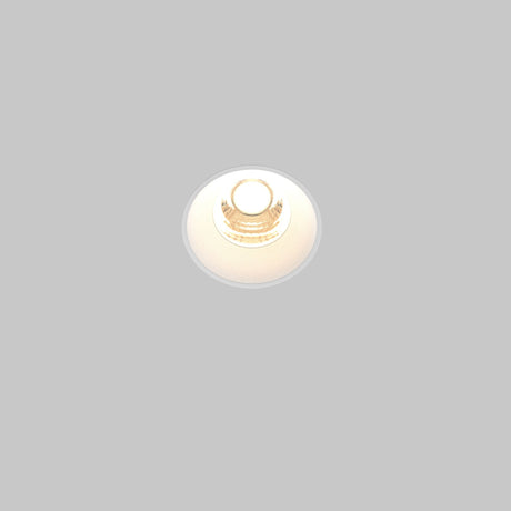 A Round LED Recessed Trimless Downlight 7W 3000K - White is illuminated against a plain gray background, emitting a soft, warm glow.