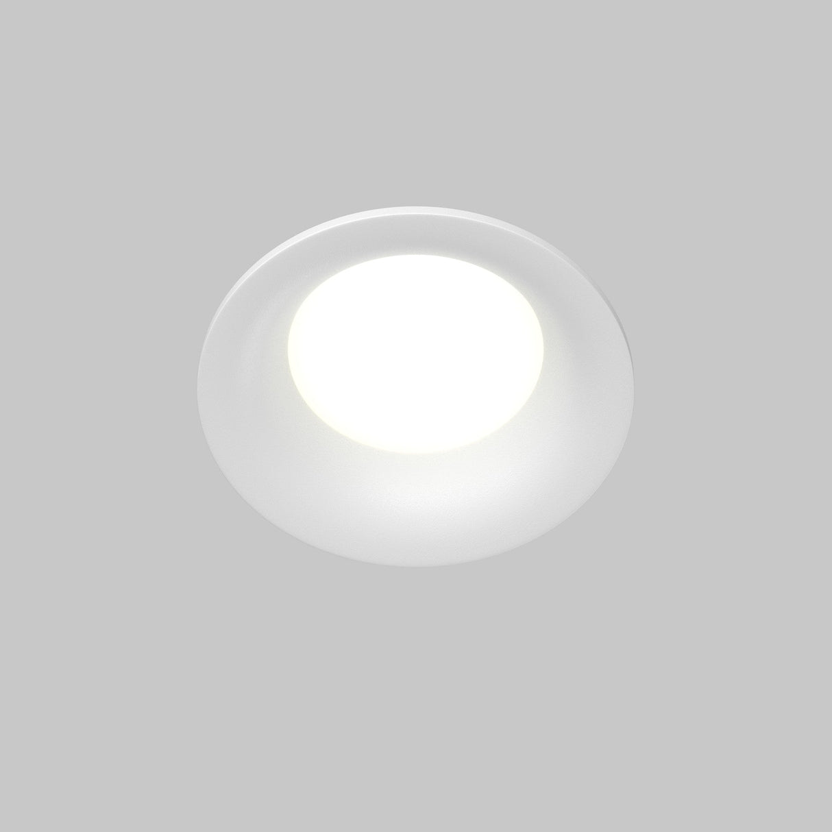 The Slim Outdoor Fixed Round Recessed Downlight - White emits a bright, soft light against a light gray background. Its clean, minimalistic design offers a modern aesthetic and is GU10 bulb compatible for versatile use.