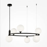 The Ring 6 Light Circular Suspension features a sleek black metal frame with six frosted white glass globes suspended at different heights by thin wires. The fixture is ceiling-mounted with a central rod and offers adjustable height for versatile elegance.