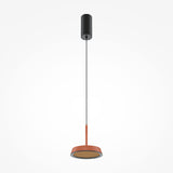 The El LED Round Tablet Pendant Light - Black & Terracotta showcases an industrial and artistic design with a black cylindrical ceiling mount, slim black cord, and terracotta circular shade. Its energy-efficient LED lights up elegantly against a white backdrop.