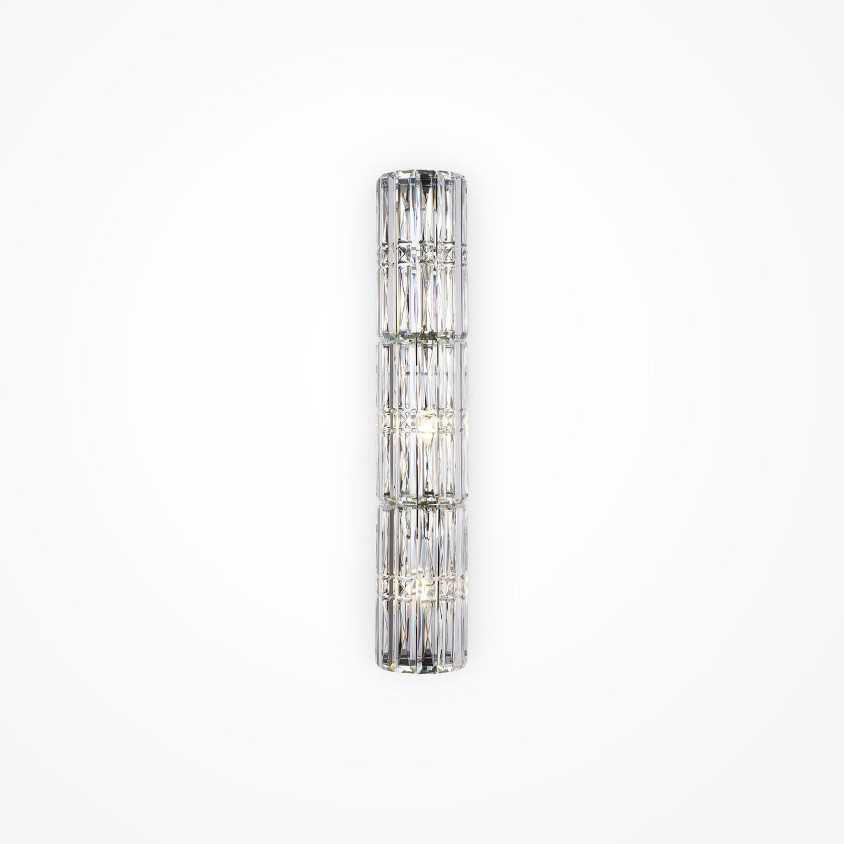 The Facet 3 Light Long Wall Light in chrome is a vertical cylindrical glass sconce with crystal and faceted panel detailing, emitting a soft, diffused light. Mounted on a plain white wall, it adds an elegant and modern touch to any space.