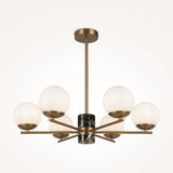 The Marble 6 Light Chandelier - Brass showcases a central black marble accent, six opal glass globes on gold metal arms, and is elegantly suspended from a brass frame and ceiling mount. It skillfully merges modern and classic design elements.