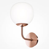 The Erich 1 Light Wall Light features a brass curved arm with a circular white glass shade and a round bronze wall-mounted base, embodying an elegant minimalistic design.