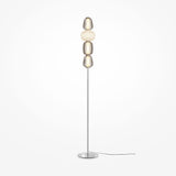 The Pattern LED Floor Lamp - Chrome is a tall, modern lamp with a slim metal stand and circular base featuring stacked spherical shades in shiny metallic and frosted white finishes, enhanced by chrome fittings, with an energy-efficient power cord.