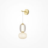 The Pattern LED Wall Light - Gold has a modern design with a gold metal base, vertical rod, and textured glass bulb holder. It features a frosted globe shade for energy-efficient illumination against a white backdrop.