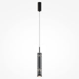 The Ordo LED Short Pendant Light, featuring a sleek cylindrical black housing and smoky glass, hangs by a thin wire from the ceiling, providing focused downward illumination.